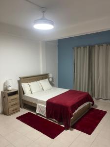 a bedroom with a bed with a red blanket at Apartamentos Santiago - Praia in Praia