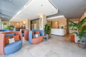 a lobby with blue and orange chairs and plants at Petit Hotel in Caorle