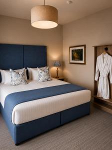 a bedroom with a large bed with a dress hanging on the wall at Powerscourt Arms Hotel in Enniskerry