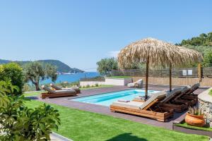 a pool with lounge chairs and a straw umbrella at Marani Villas Collection in Skopelos Town