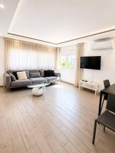 a living room with a couch and a television at Royal Lea Apartmens in Netanya