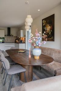 a vase of flowers on a wooden table in a kitchen at Luxe villa aan golfbaan en bosrand in Appelscha in Appelscha