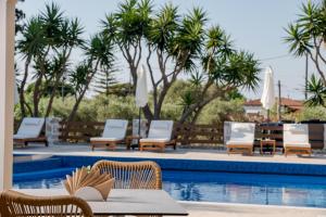 a pool with chairs and a table next to a pool at Noma Vasilikos in Vasilikos