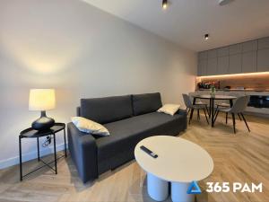 a living room with a couch and a table at 365PAM - Apartament Sea & Forest - BASEN KRYTY I ZEWNĘTRZNY, JACUZZI, SAUNA, GARAŻ W CENIE in Międzyzdroje