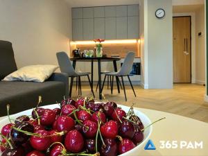 a bowl of cherries on a table in a living room at 365PAM - Apartament Sea & Forest - BASEN KRYTY I ZEWNĘTRZNY, JACUZZI, SAUNA, GARAŻ W CENIE in Międzyzdroje