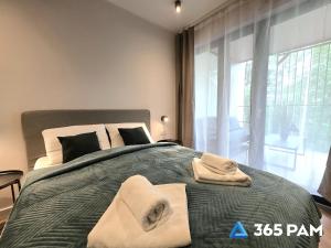 a bedroom with a large bed with towels on it at 365PAM - Apartament Sea & Forest - BASEN KRYTY I ZEWNĘTRZNY, JACUZZI, SAUNA, GARAŻ W CENIE in Międzyzdroje