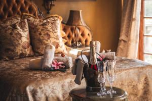 a bed with a table with wine glasses on it at Vineam Castle - Manor Guesthouse in George