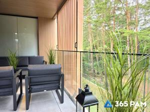 a patio with chairs and a large glass window at 365PAM - Apartament Sea & Forest - BASEN KRYTY I ZEWNĘTRZNY, JACUZZI, SAUNA, GARAŻ W CENIE in Międzyzdroje