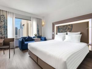 a hotel room with a large bed and a blue chair at Novotel Bangkok on Siam Square in Bangkok