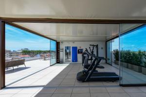 a gym with glass doors and a treadmill at Petit Hotel in Caorle