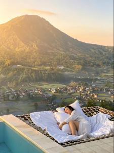 Eine Frau liegt auf einem Bett, im Hintergrund ein Berg. in der Unterkunft Hidden Hill in Gretek