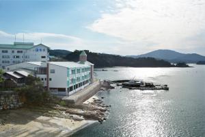 une grande étendue d'eau avec un bâtiment et un bateau dans l'établissement Uminoyasuragi Hotel Ryugu, à Kami Amakusa