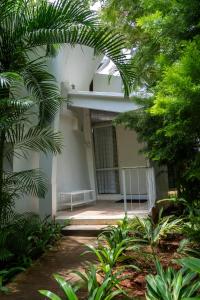 a white building with a gate and some trees at Trisara Boutique Stay in Mysore