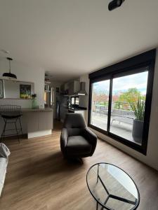 a living room with a chair and a glass table at EXCLUSIVO PENTHOUSE EN CORDON SOHO con parrillero in Montevideo