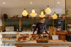 a woman is standing behind a counter with food at Hôtel Kemaris in Biarritz
