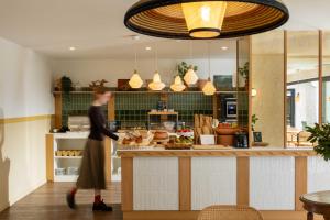a woman walking past a counter in a kitchen at Hôtel Kemaris in Biarritz