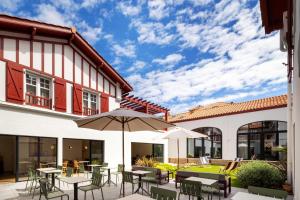 an outdoor patio with tables and chairs and an umbrella at Hôtel Kemaris in Biarritz +16 photos