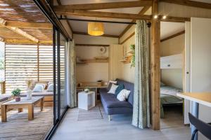 a living room with a couch and a bed in a room at Camping les vergers de Squividan *** in Tréffiagat
