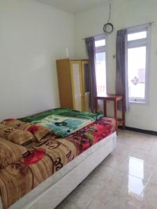 a bedroom with a bed and a table and windows at Lusman Homestay Bromo in Ngadisari