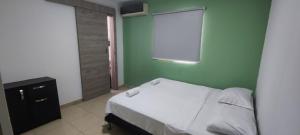 a green bedroom with a bed and a window at Oasis in Valledupar