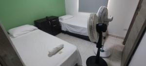 a small room with two beds and a fan at Oasis in Valledupar