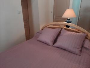 a bed with purple sheets and a lamp at La Maison Méditerranéenne in La Ciotat