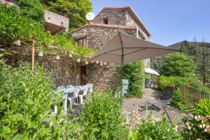 a table with an umbrella in front of a building at La Clé de l'Arboux in Mandagout