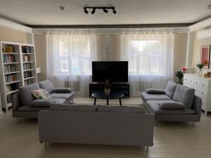a living room with two couches and a flat screen tv at Bükfürdő Kúria Apartman Stúdió, Bükfalva in Bükfürdő