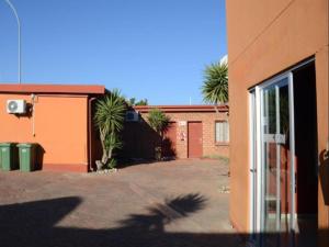 a building with palm trees next to a driveway at Oluzizi Guesthouse in Windhoek +8 photos