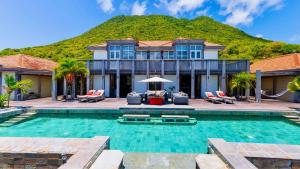 a house with a swimming pool with a mountain in the background at Whale Tails Island Suites & Villas in Oranjestad