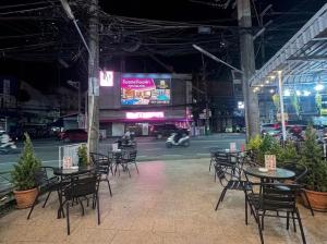 a group of tables and chairs in a building at night at Best Inn Hostel and Café Patong Beach in Patong Beach