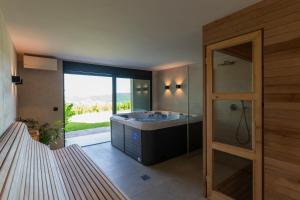 a bathroom with a tub and a shower with a window at Blacksmith house - SPA, Heated outdoor pool, Kids zone in Varaždinske Toplice