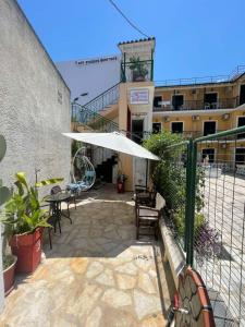 a patio with a white umbrella and a building at Art Studios Benitses in Benitses