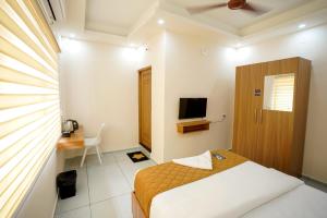 a bedroom with a bed and a desk and a television at Misty Suite Infopark in Cochin