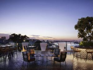 a restaurant with tables and chairs on a rooftop at TRIBE Phnom Penh Post Office in Phnom Penh