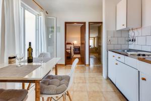 a kitchen with white cabinets and a table with a bottle of wine at Apartmani Katica in Diklo