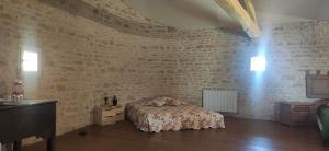 a bedroom with a bed and a brick wall at Le Gîte et le Couvert in Bellefoye