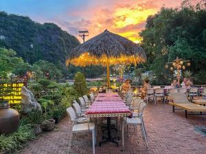 a patio with a table and chairs and an umbrella at Tam Coc Central Backpacker Hostel in Vũ Lâm