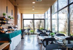 a dining room with tables and chairs and windows at Verdemilia Hotel in Anzola dell'Emilia