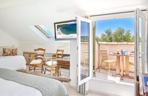 a bedroom with a bed and a balcony with a table and chairs at La Ferme D'Augustin in Saint-Tropez