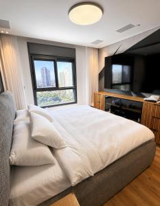 a large white bed in a room with a television at דירת החלומות באשדוד in Ashdod