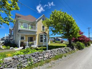 a yellow house with a stone wall at Louisbourg Harbour Inn in Louisbourg
