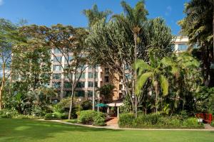 a building with palm trees in front of a park at Nairobi Serena Hotel in Nairobi