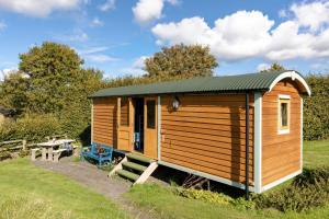 a wooden cabin in a field with a picnic table at Teasel Shepherd's Hut in Berwick-Upon-Tweed +9 photos