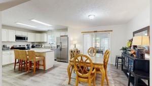 a kitchen with white cabinets and a table and chairs at Piney Glade - 18628 Sylvan Dr in Rehoboth Beach