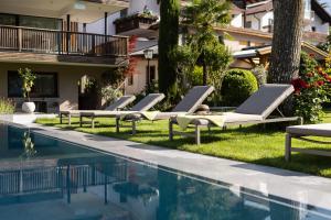 a row of lounge chairs next to a swimming pool at Apartm. & BB Ferienidylle Gstrein in Rablà