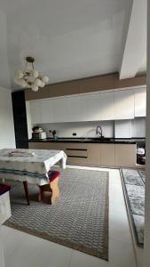 a kitchen with a table and a kitchen with white cabinets at datkaguesthouse in Kochkorka