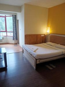 a bedroom with a large bed in a room with a window at Hotel J'S Heritage in Kodaikānāl +6 photos