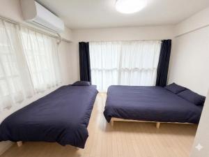 a bedroom with two beds and a window at メゾンドアトール in Sapporo