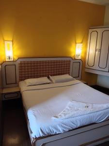 a bed in a bedroom with two lights on the wall at Hotel J'S Heritage in Kodaikānāl